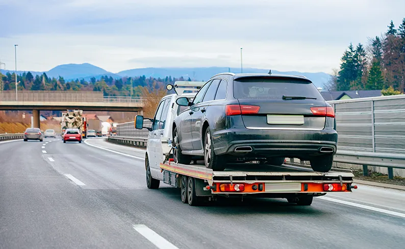 A car being towed on a flatbed truck.